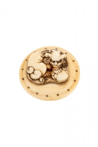 Netsuke en ivoire représentant un Shishi accroupi sur un tambour