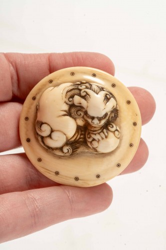 XIXe siècle - Netsuke en ivoire représentant un Shishi accroupi sur un tambour